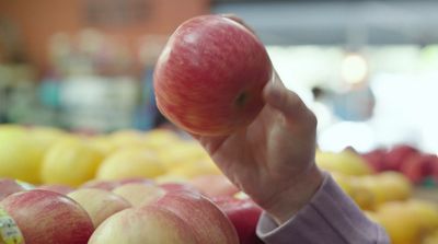 a person holding an apple in front of a display of apples