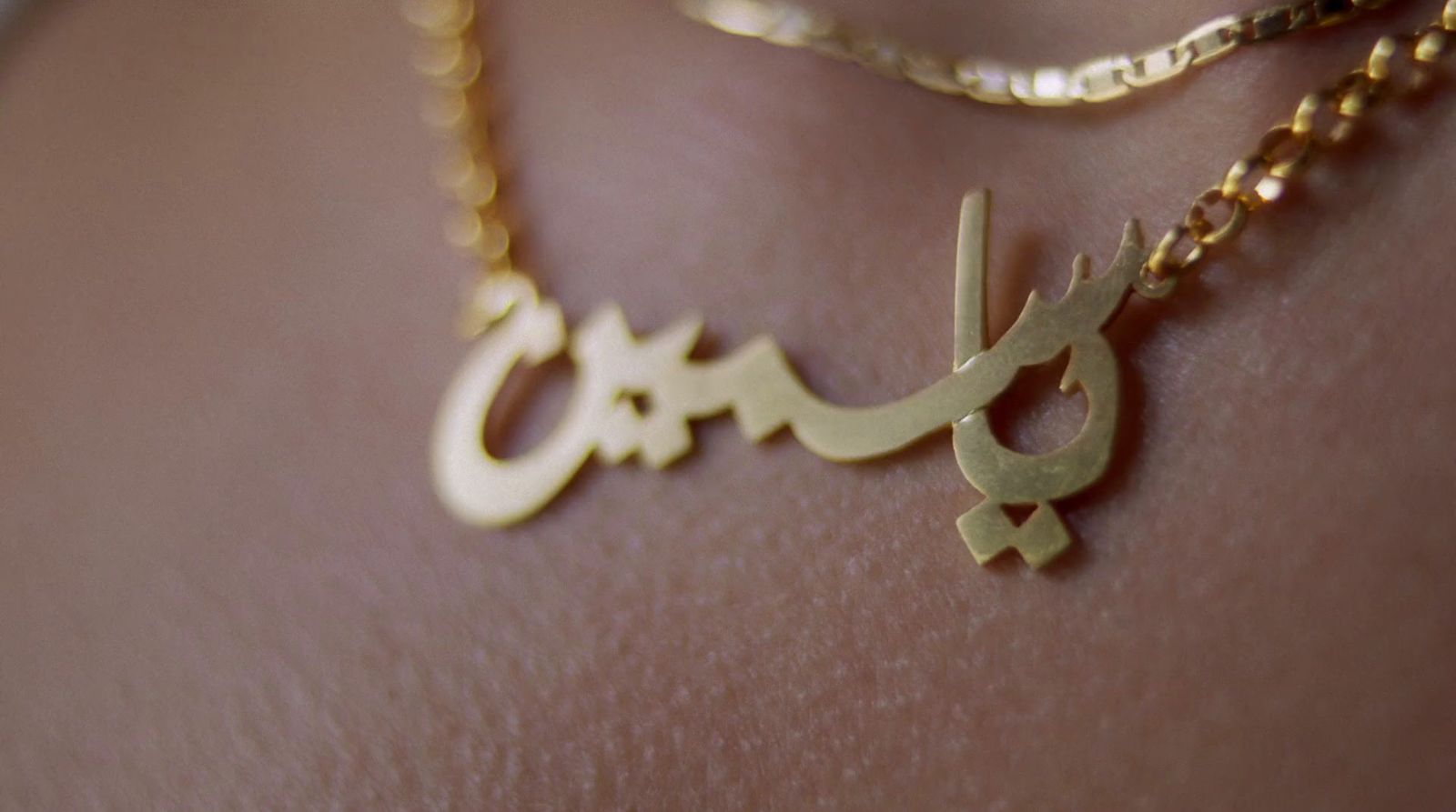 a close up of a person wearing a gold necklace