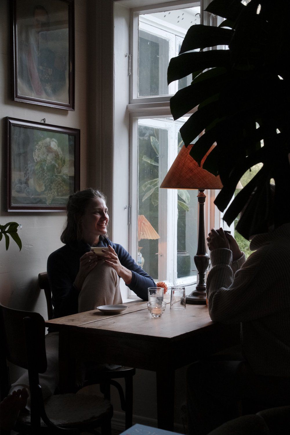 a woman sitting at a table in front of a window