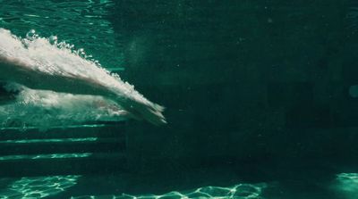 a man is swimming in a pool with his feet in the water