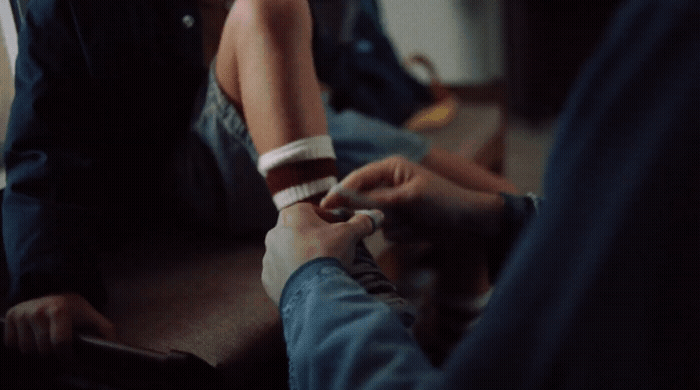 a person sitting on the ground with a cigarette in their hand