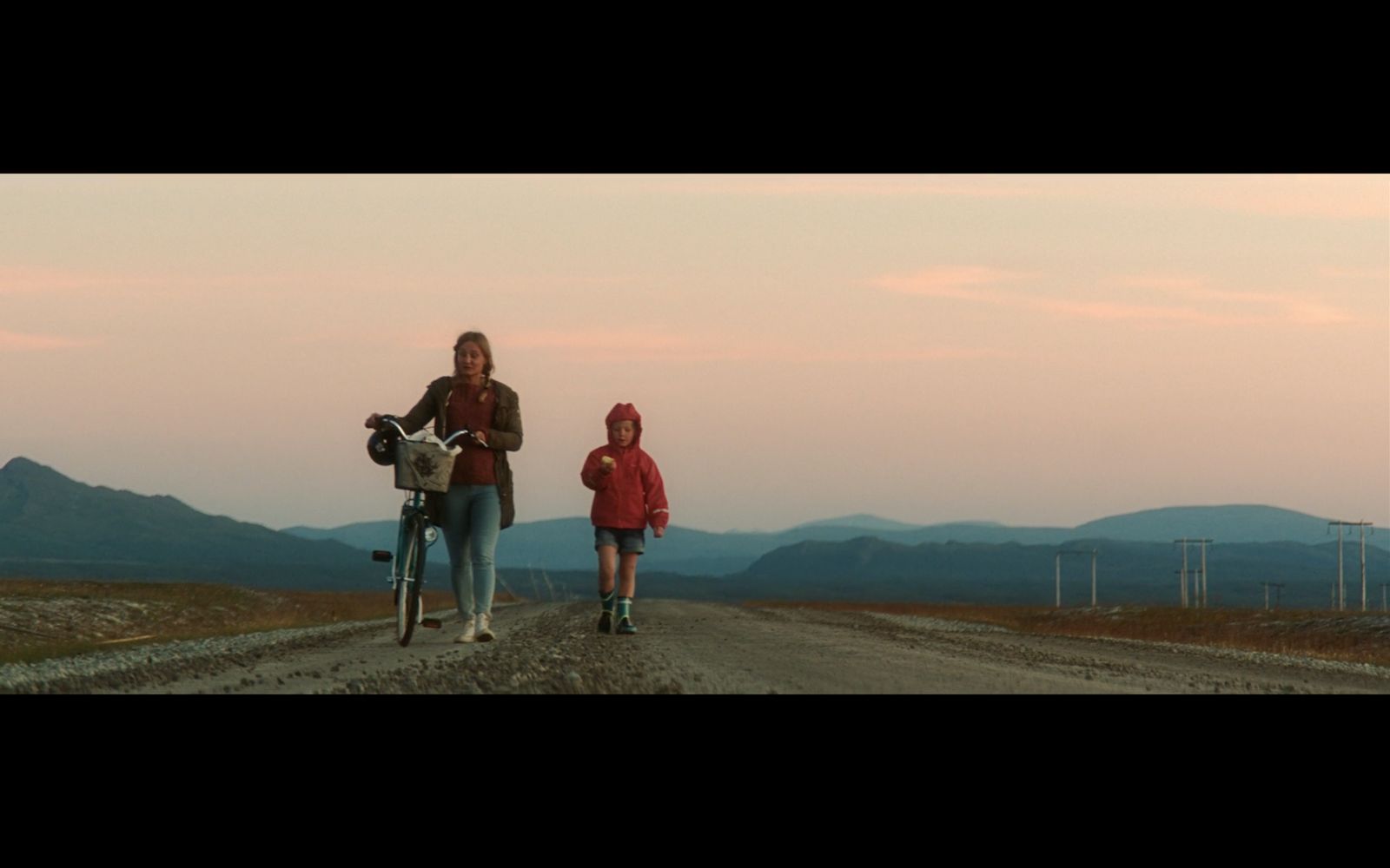 a couple of people walking down a dirt road