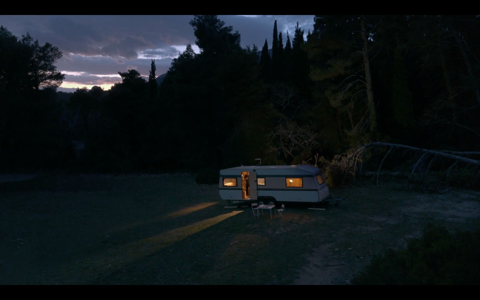 a camper parked in the middle of a forest at night