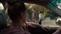 a woman sitting in a car with her hand on the steering wheel