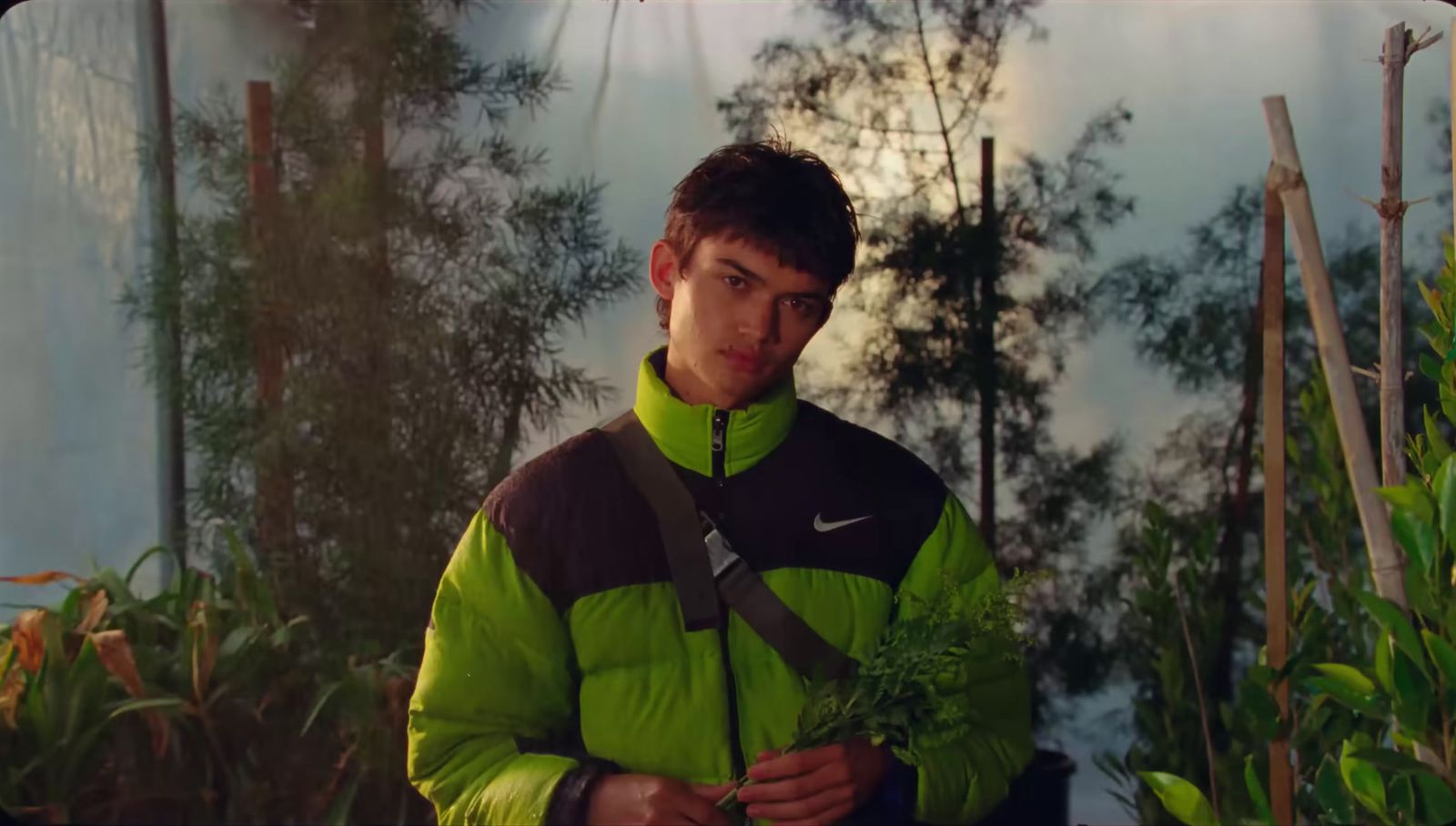 a man in a green jacket holding a plant