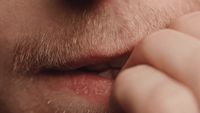 a close up of a man putting something in his mouth