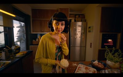 a woman standing in a kitchen holding a piece of bread