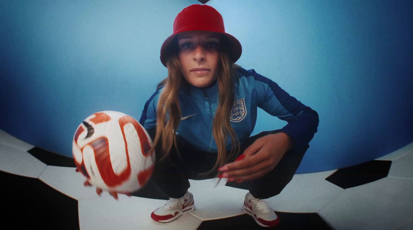 a girl in a red hat is holding a soccer ball