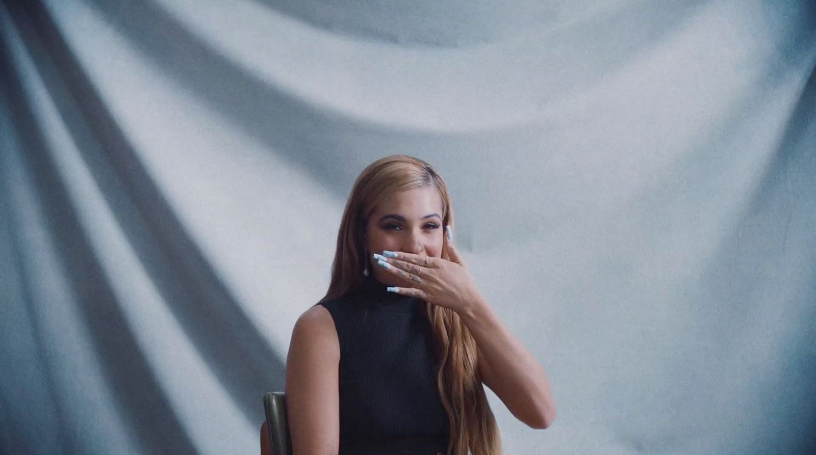 a woman sitting in a chair with a cigarette in her mouth