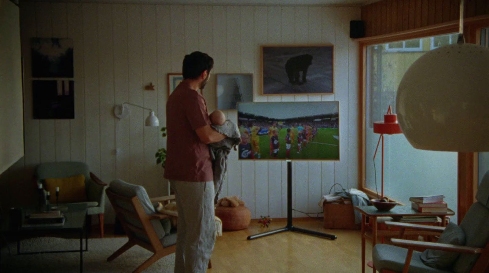a woman standing in a living room holding a baby