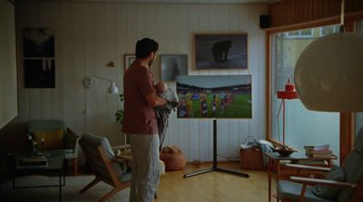 a woman standing in a living room holding a baby
