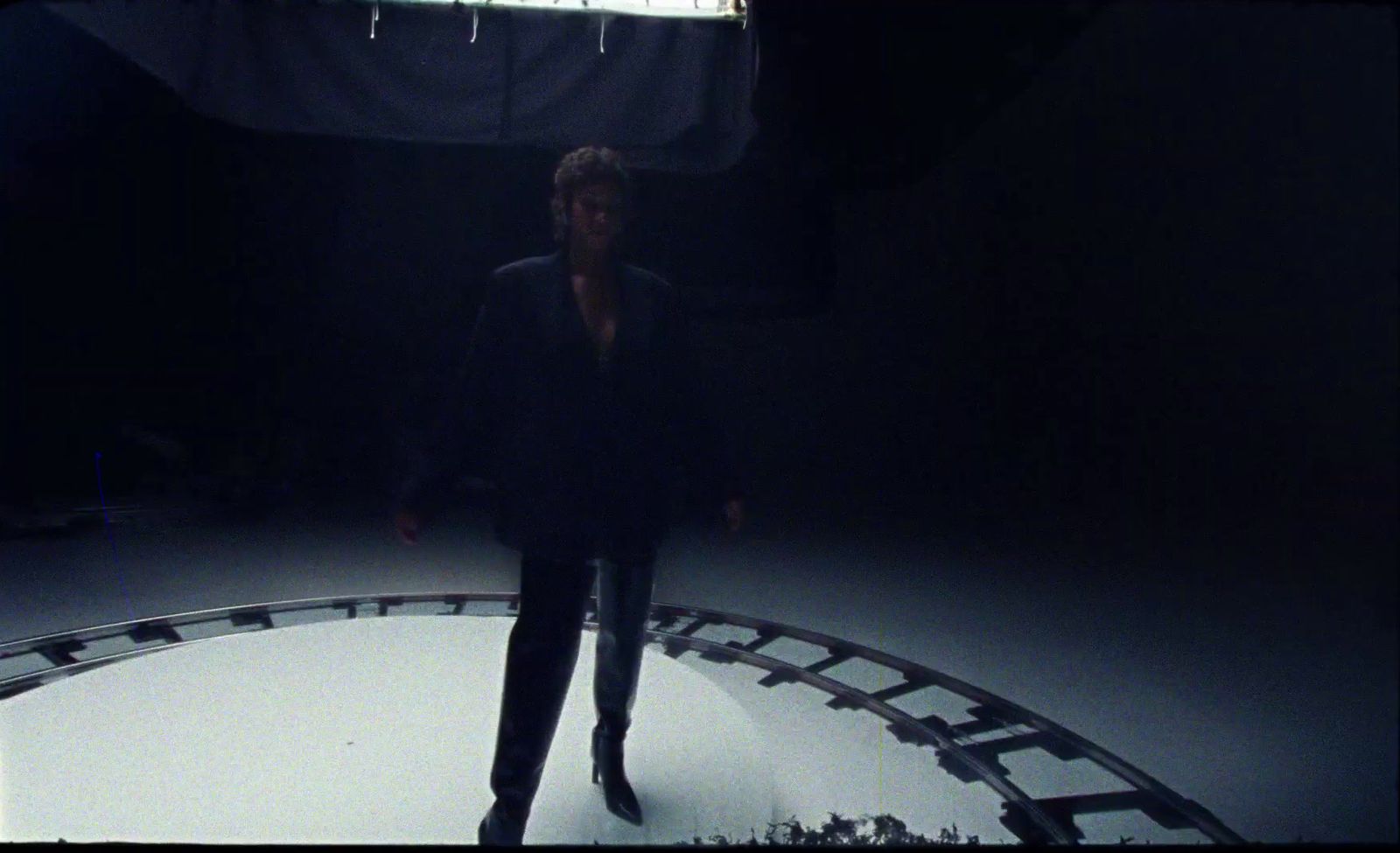 a woman standing in a dark room next to a clock