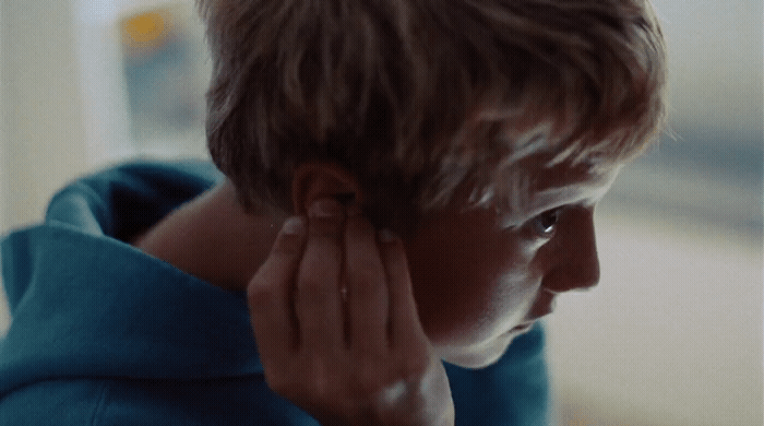 a young boy is holding his ear to his ear