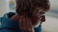 a young boy is holding his ear to his ear
