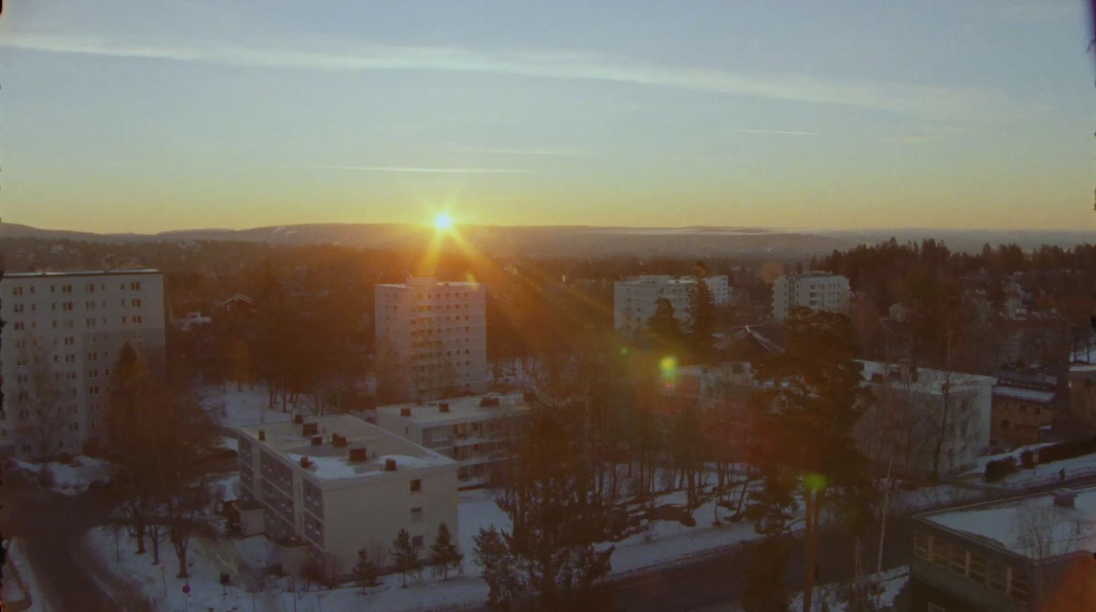 the sun is setting over a city in winter