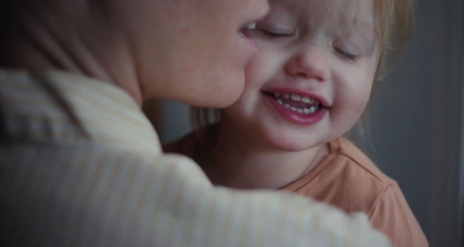a little girl is kissing a woman's face