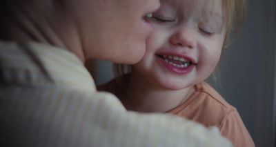 a little girl is kissing a woman's face