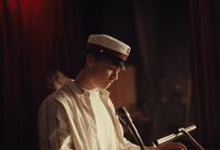 a man in a sailor's hat sitting in front of a microphone