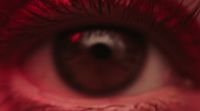 a close up of a person's eye with red light reflected in it