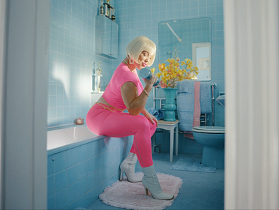 a woman in a pink outfit is sitting on a bathtub