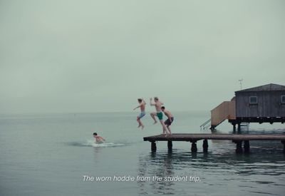 a group of people jumping off a dock into the water