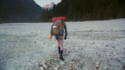 a person with a backpack walking across a river