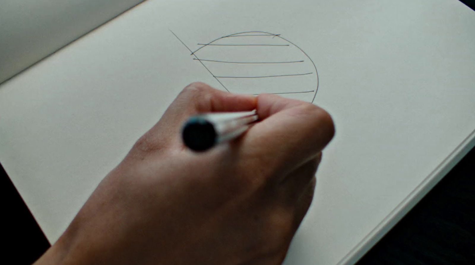 a person drawing a ball on a piece of paper