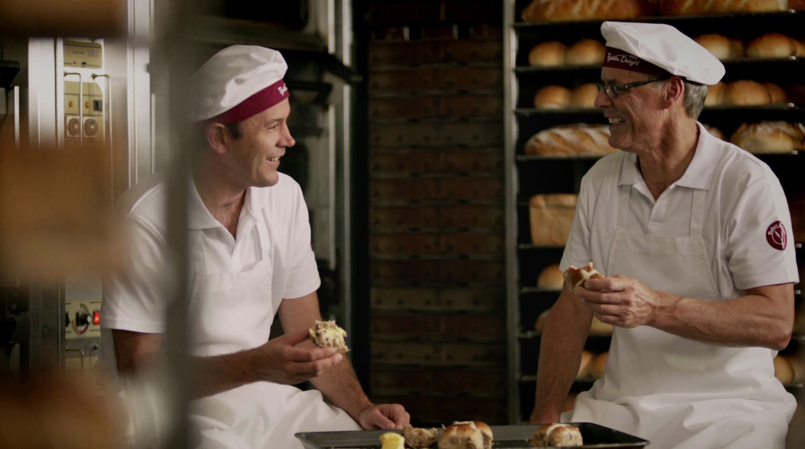 a couple of men sitting next to each other in a kitchen