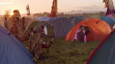 a group of people sitting in a field next to tents