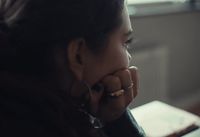 a woman sitting at a table with her hand on her face