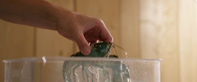 a person holding a mouse in a plastic container