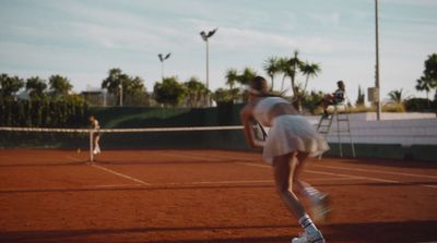 a woman in a white dress playing a game of tennis