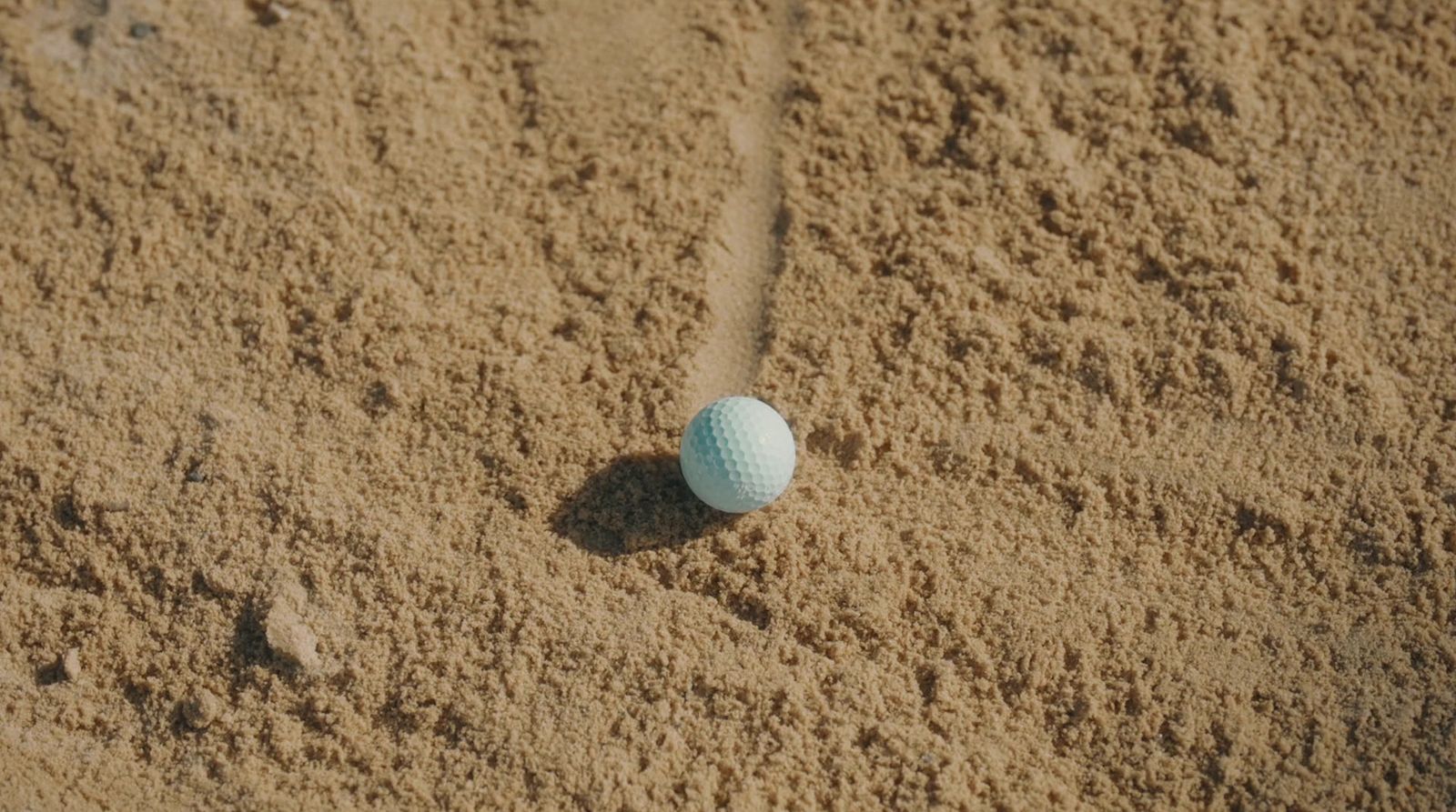 a golf ball sitting in the sand on a beach