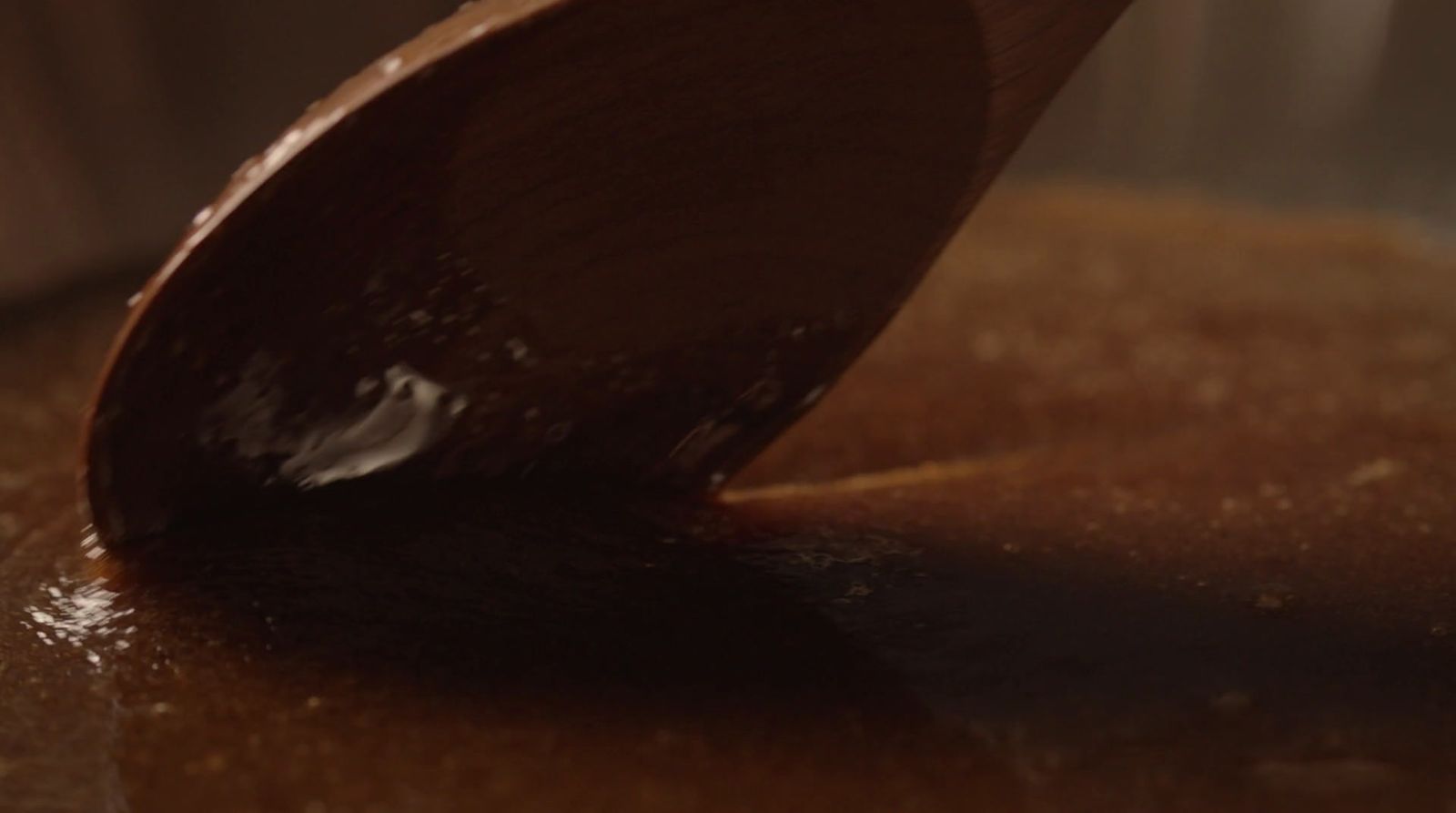 a wooden spoon stirring chocolate into a pot