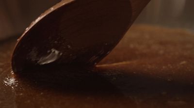 a wooden spoon stirring chocolate into a pot