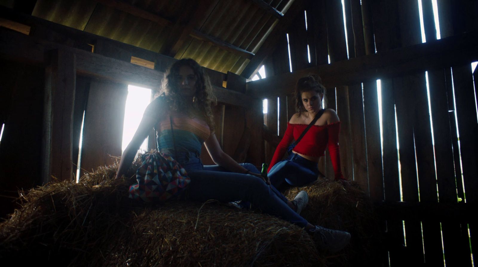 a couple of women sitting on top of a pile of hay