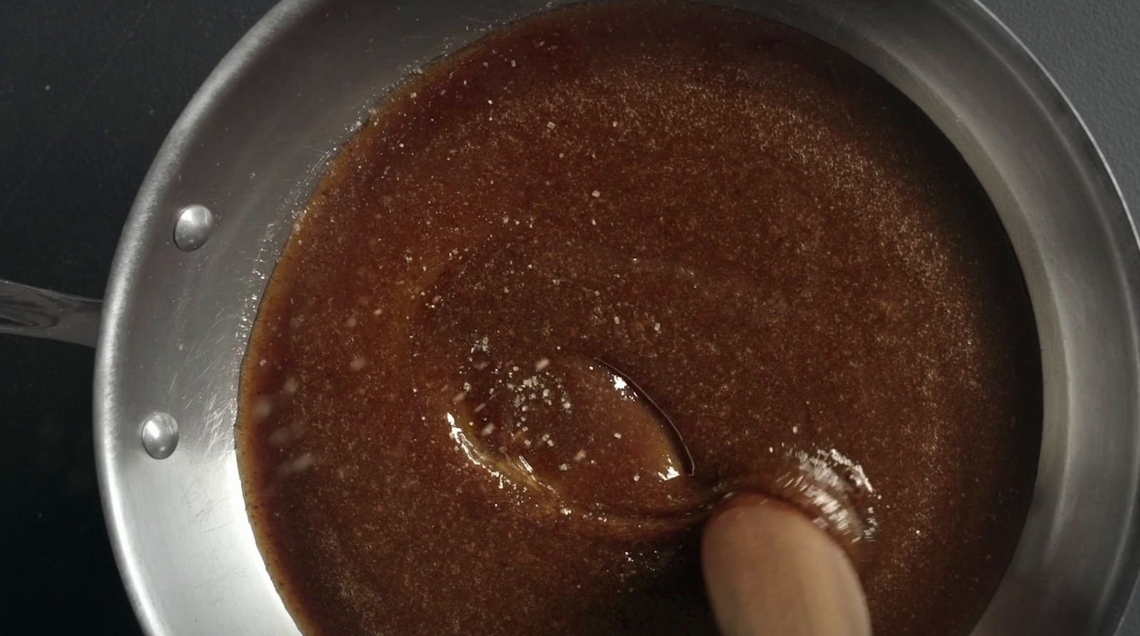 a person stirring a sauce in a saucepan