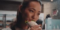 a woman eating a burrito in a fast food restaurant