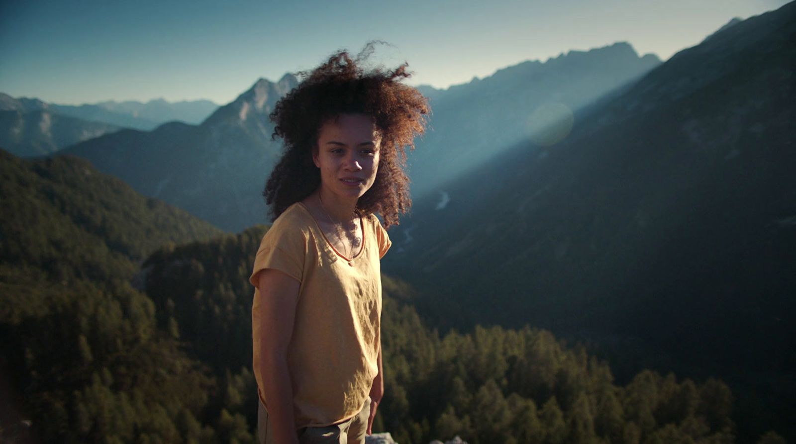 a woman standing on top of a lush green hillside