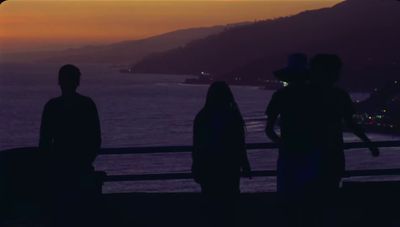 a group of people standing next to each other near the ocean