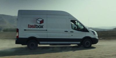 a white delivery truck driving down a dirt road