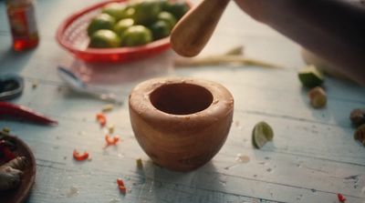 a wooden bowl filled with green vegetables on top of a table