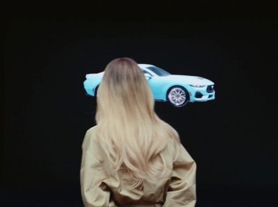 a woman standing in front of a blue car