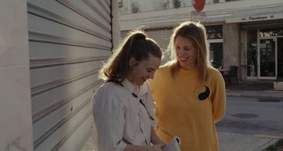 two women standing next to each other near a building