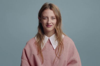 a woman with long hair wearing a pink sweater