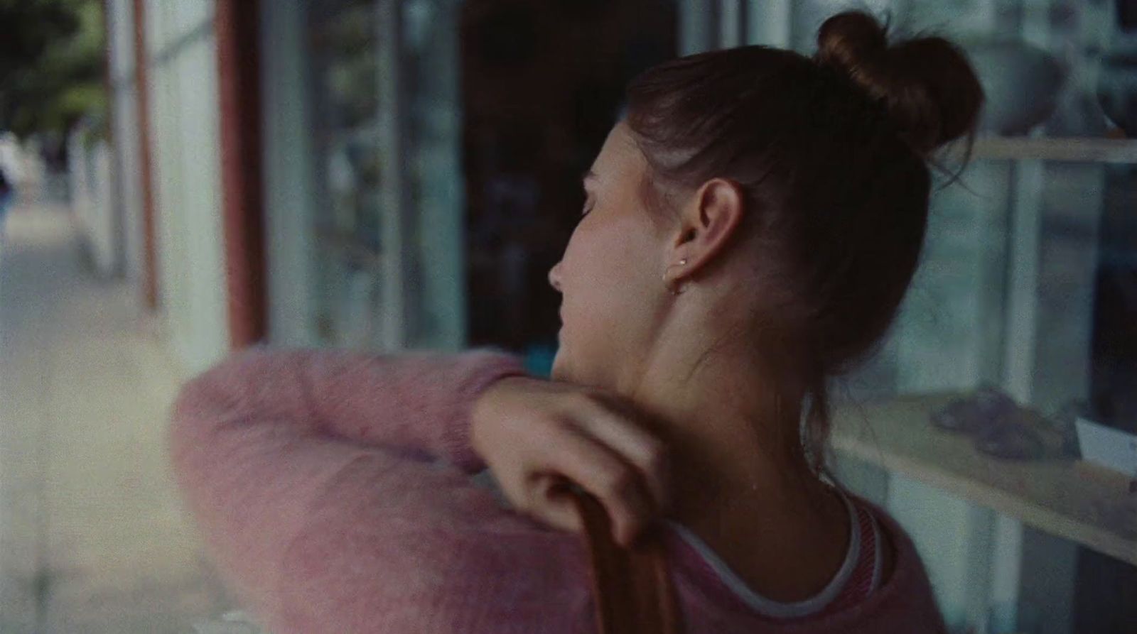 a woman in a pink sweater looking out a window