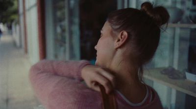 a woman in a pink sweater looking out a window