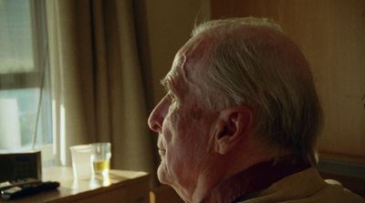 an older man looking out a window at the outside