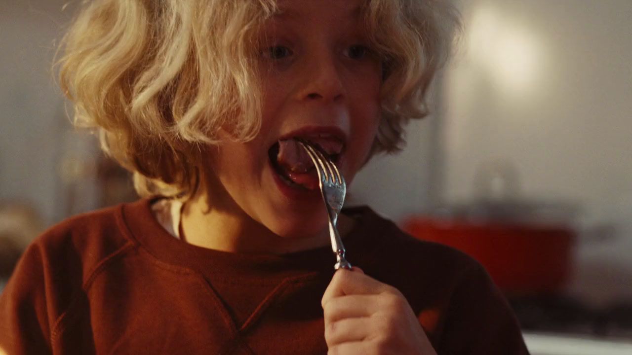 a young child is eating a fork in the kitchen