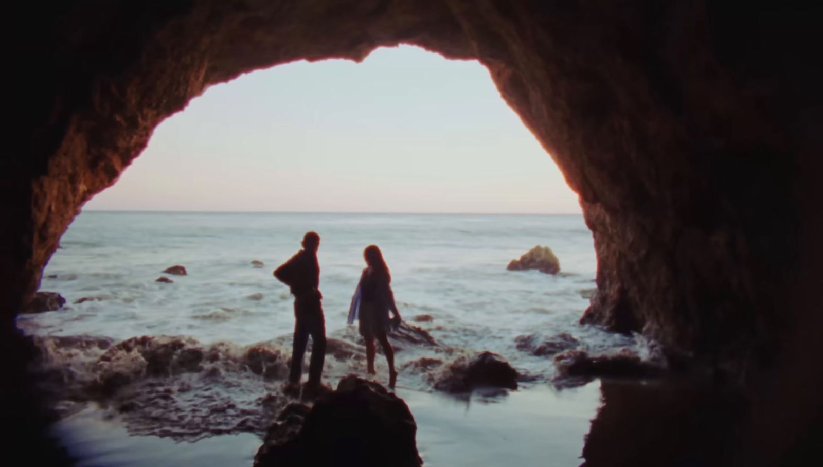 a couple of people standing on top of a beach near the ocean